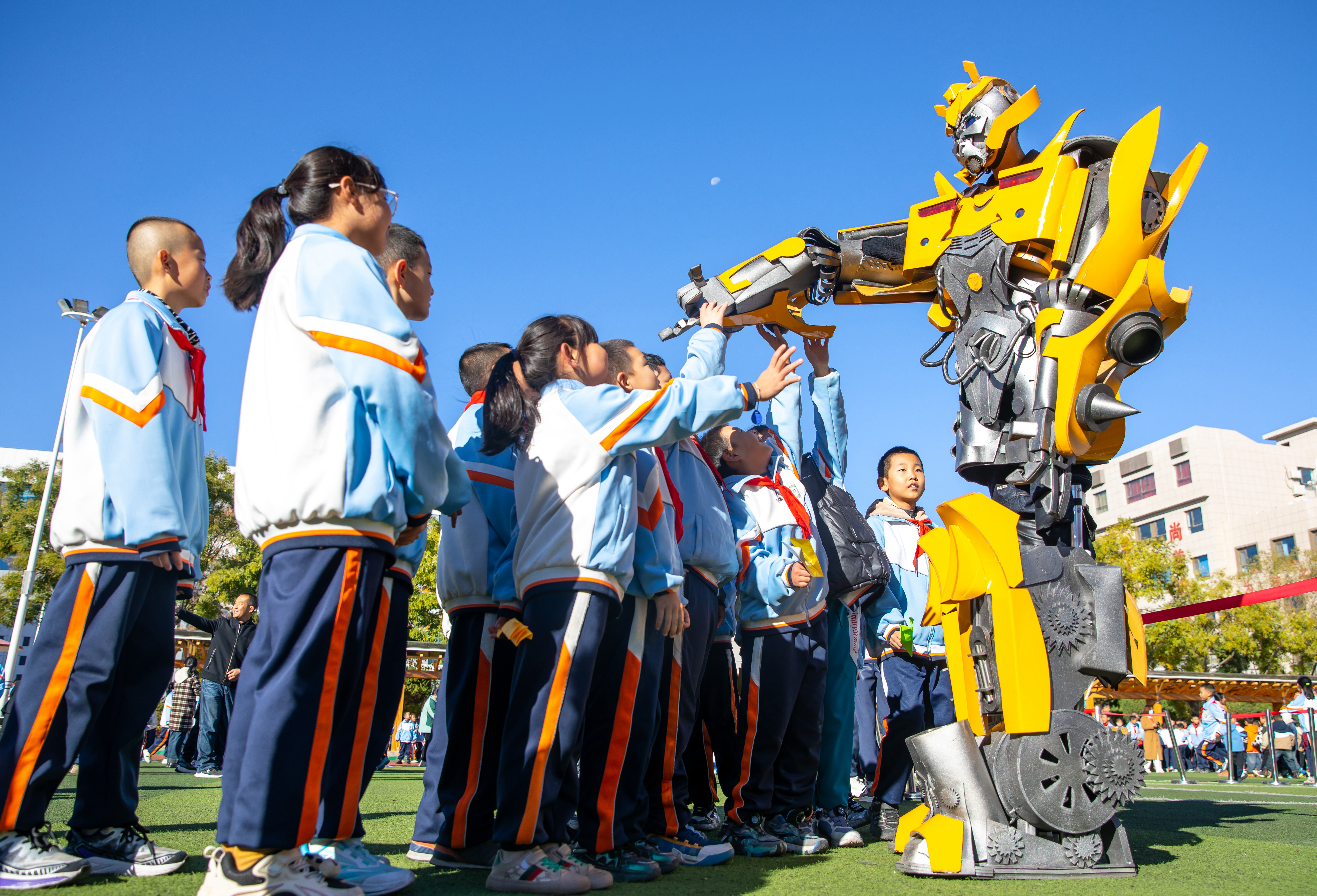 2024年10月22日，在甘肅省張掖市甘州區(qū)北街街小學(xué)科技大篷車嘉年華活動(dòng)上，學(xué)生與“大黃蜂”機(jī)器人互動(dòng)。楊瀟 攝.jpg