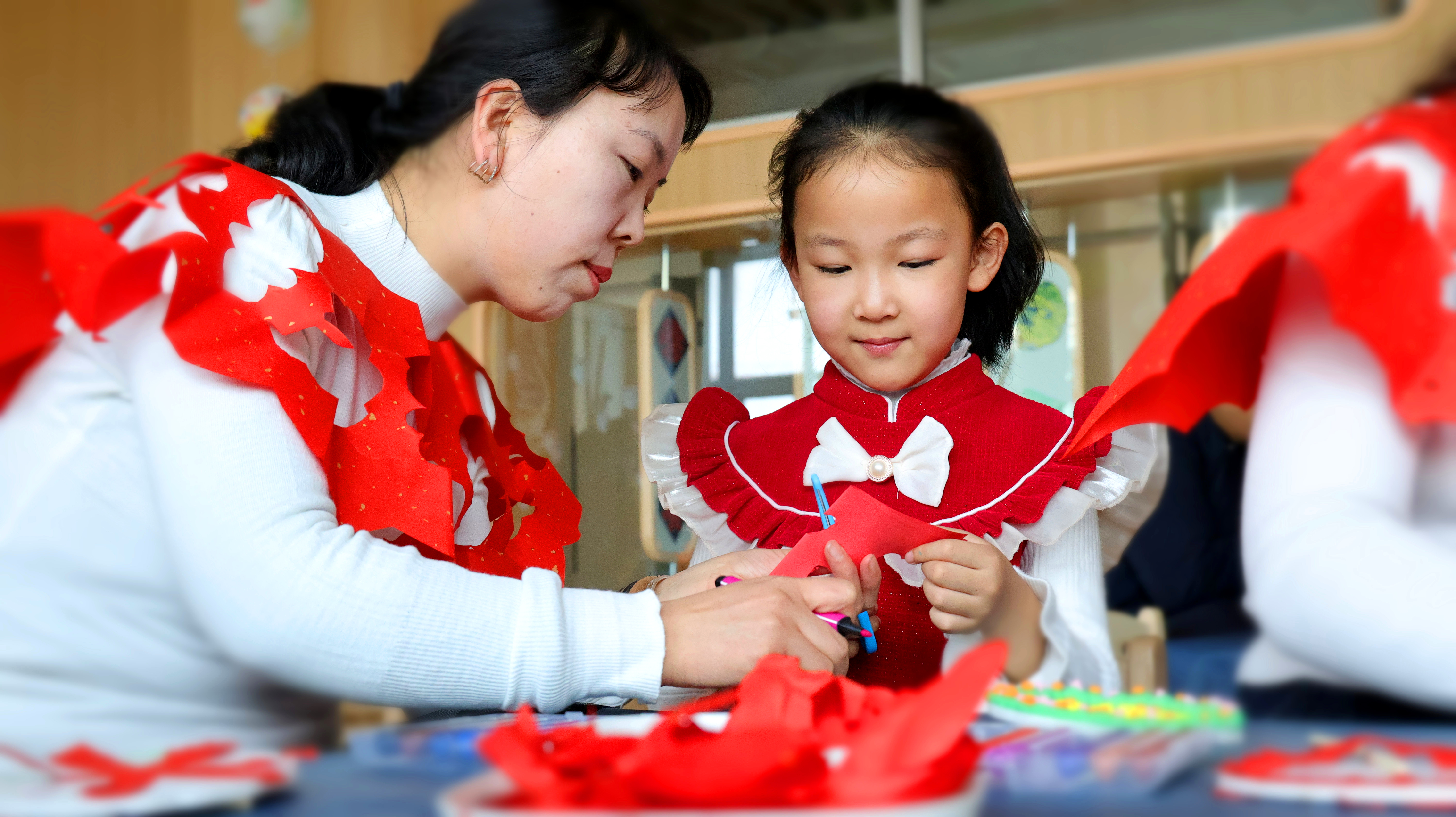 幼兒和媽媽一起用剪紙的方式制作云肩。宋雪蓮攝.jpg