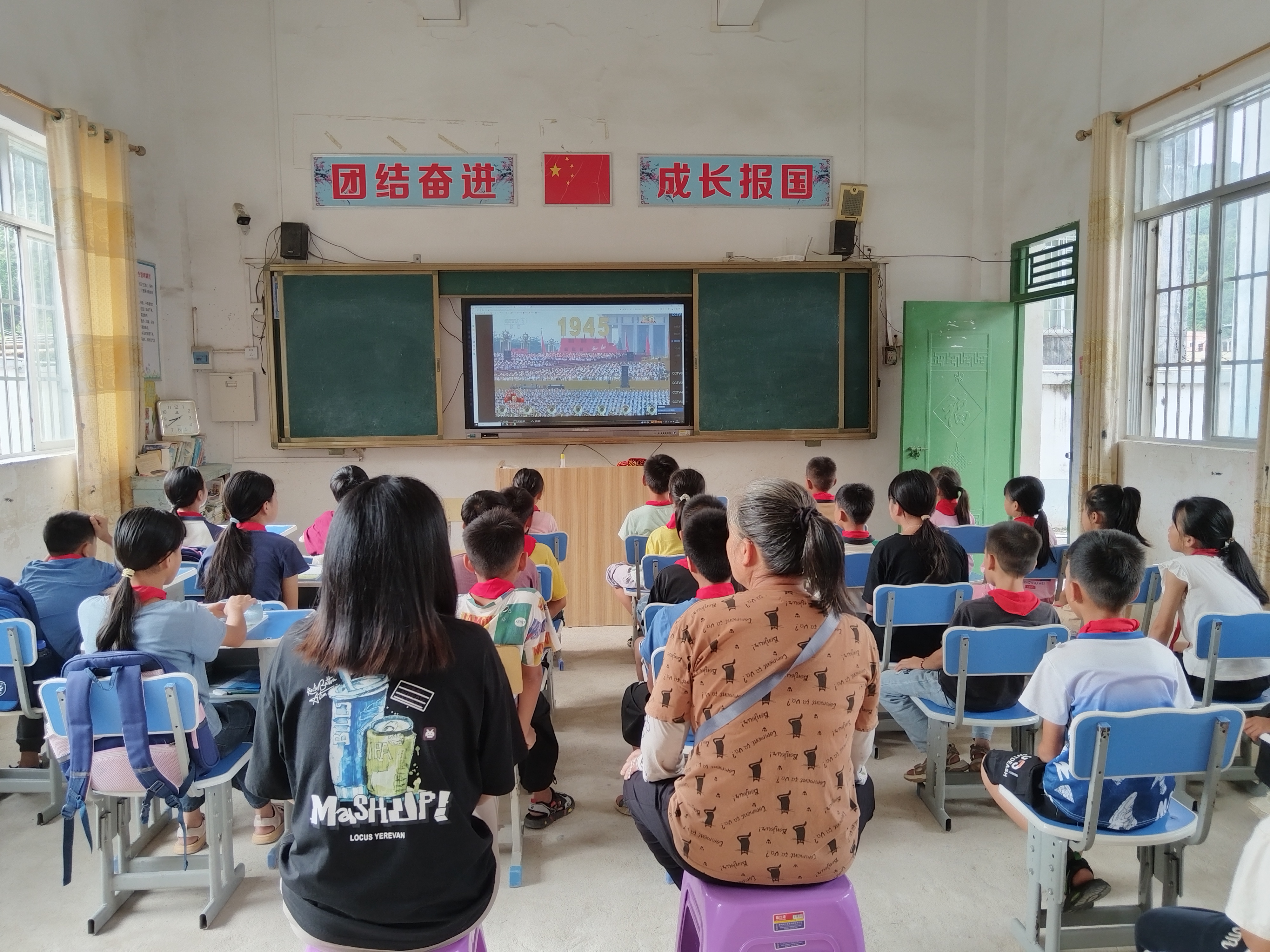 欽北區(qū)板城鎮(zhèn)高龍小學家長和學生一起觀看閱兵儀式。.jpg