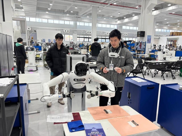 浙江工商職業(yè)技術(shù)學(xué)院“普智未來”訂單班學(xué)生在調(diào)試機(jī)器人 學(xué)校供圖.png